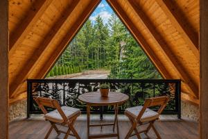 a table and two chairs on a balcony with a window at Brvnara Mont in Zlatibor