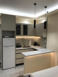 a kitchen with white cabinets and a white refrigerator at Drenos Rooms view in Kallithea Halkidikis +59 photos
