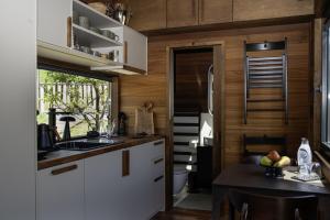 a kitchen with white cabinets and a sink and a table at Gradmina Glamping Retreat in Prevala