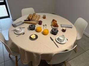 a white table with bread and oranges on it at Chambre d'hôte l'Argentier in Noyarey