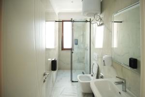 a white bathroom with a sink and a toilet at Velorè Boutique Hotel in Tirana