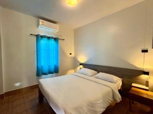 a bedroom with a large bed with a blue window at Coconut Bungalow in Nai Yang Beach
