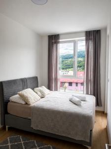 a bedroom with a bed and a large window at AURA apartment Vogošća, Sarajevo in Vogošća