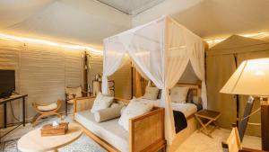 a bedroom with a canopy bed with a couch at The Kharma Villas Yogyakarta in Yogyakarta