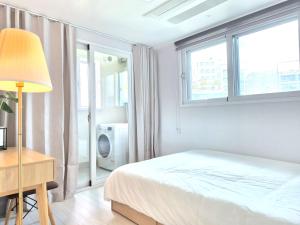 a white bedroom with a bed and a window at Stayrium Sagajeong in Seoul