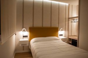 a bedroom with a large bed with two lights on it at Alojamientos El Parque in Rute