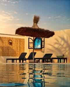 a patio with chairs and an umbrella next to a swimming pool at The Mogador's Oasis in Akermoud