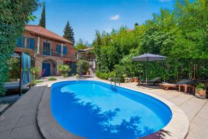 a large blue swimming pool in a yard with an umbrella at VILLA Mara in Dubravka