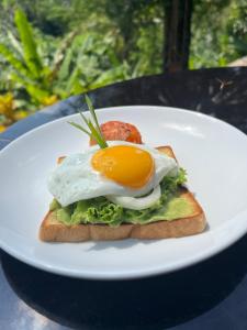 an egg on top of a piece of bread on a plate at Sidemen padi villas in Silebeng