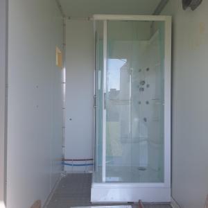 a glass shower stall in a white room with at Caravane Les Roches Blanches in Guenroc