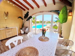 a dining room with a table and chairs and a pool at Villa Gota de Mar in Jávea