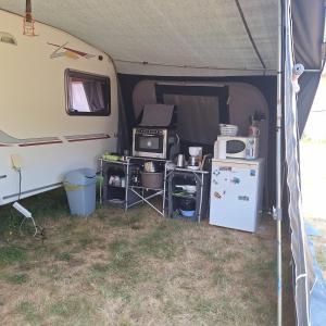 an inside of a tent with a kitchen and refrigerator at Caravane Les Roches Blanches in Guenroc