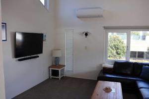 a living room with a black couch and a flat screen tv at Beachfront Marine Parade in Mount Maunganui