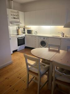 a kitchen with a table and chairs and a kitchen with white cabinets at The South Wing at Højbygård in Rødby