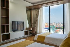 a hotel room with a bed and a television at Champs Elysees Hotel & Suites in Phnom Penh