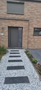 a brick building with a garage door and a gravel driveway at Chambre d'hôte Escale piscine in Ghislenghien