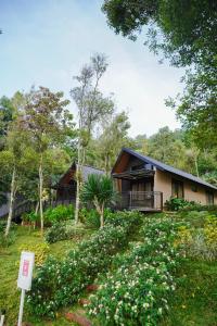 a house in the middle of a yard with flowers at Teras Bumi Cabin in Haurkuning