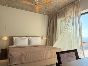 a bedroom with a bed with a ceiling fan and a window at KITO suites in Kitriaí