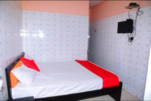 a small bedroom with a white bed with red pillows at Chhatrapati Residency in Tirupati