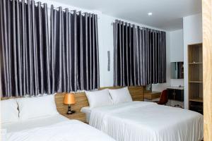 two beds in a room with black and white curtains at Khách sạn Caravelle Cần Thơ 2 in Can Tho +14 photos