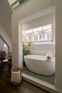 a large white bath tub in a bathroom with a window at Hanachi Stay in Ho Chi Minh City