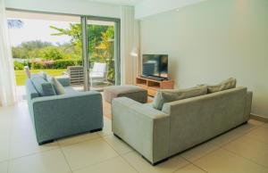 a living room with two couches and a television at Seafront apartment in Grande Gaube