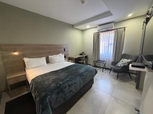 a bedroom with a bed and a desk and a chair at The Royal Gem Hotel in Jwaneng