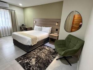 a bedroom with a bed and a chair and a mirror at The Royal Gem Hotel in Jwaneng
