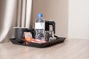 a bottle of water and glasses in a tray on a table at The Royal Gem Hotel in Jwaneng