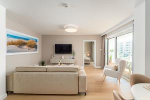 a living room with a couch and a tv at POLANKI AQUA APARTAMENTY - Aquapark, baseny, wellness, 300 m od plaży in Kołobrzeg
