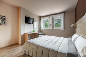 a bedroom with a large bed and two windows at Iraipe Santuario de Arantzazu Hotel in Oñati