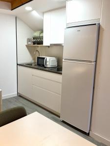 a kitchen with a white refrigerator and a microwave at Albergue -Hostel ManuelaINN in El Burgo de Osma