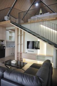 a living room with a black leather couch and a staircase at Teras Bumi Cabin in Haurkuning
