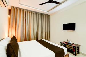 a bedroom with a bed and a flat screen tv at Hotel O Vyb Hotels in Hyderabad