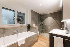 a bathroom with a bath tub and a sink at FLORA BAY Spacious Lake and Mountain View Apartment in Niederried +50 photos