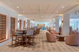 a lobby with tables and chairs in a building at Exclusive Kauai Beachfront Resort with Dining, Bar, Spa, Pool & Waterslide in Lihue