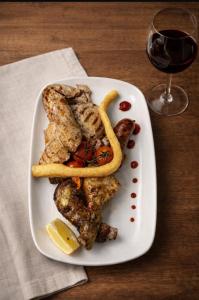 a plate of food with meat and a glass of wine at La Stazione in Cordovado +6 photos