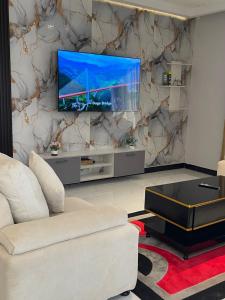 a living room with a couch and a tv on a wall at Bellwether Heights Kyanja in Kampala