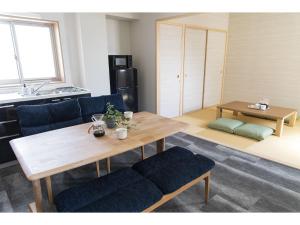 a living room with a wooden table and blue chairs at GLANZ KEI Kyoto Station in Kyoto