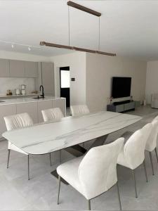 a white dining table with white chairs and a kitchen at Ste hub loges in Parakou