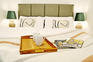 a bed with a tray on it with books and cups at Moravská 15 Apartments in Karlovy Vary
