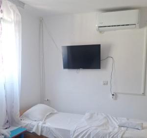 a room with a bed and a tv on the wall at Camere de închiriat Doriana in Vama Veche