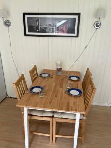 a wooden table with four chairs with plates and glasses at Spacious apartment in Kristiansand with EV Station in Kristiansand +23 photos