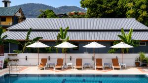 a pool with chairs and umbrellas next to a building at Rabbit Mansion Patong Hotel in Patong Beach