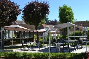 un patio avec des tables, des chaises et des parasols dans l'établissement Le Lanthenay, à Romorantin-Lanthenay