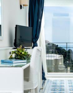 a tv sitting on a desk with a table with a window at Regina Cristina in Capri
