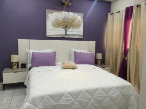 a bedroom with a large white bed with purple walls at BRUNCH RESIDENCE BoUAKE in Kodia Kofikro