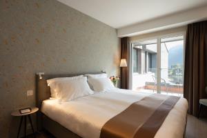 a bedroom with a large bed and a large window at Hotel Safiro in Fluelen