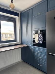 a kitchen with blue cabinets and a window at Blue Oasis Apartment - Hils Brauner in Bucharest