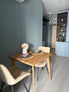 a wooden table with two chairs and a vase on it at Blue Oasis Apartment - Hils Brauner in Bucharest